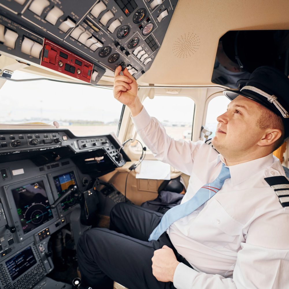 Professional worker. Pilot in formal wear sits in the cockpit and controls airplane.